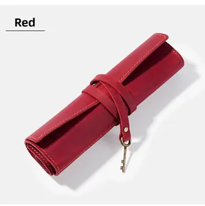 Macro detail of red crazy horse leather pencil roll with vintage bronze key pendant