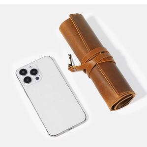 Detail of vintage brown crazy horse leather pen roll with unique metal key pendant strap
