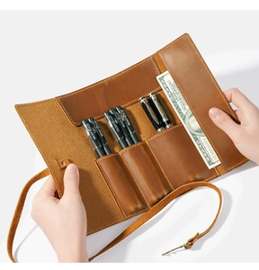 Detail of vintage brown leather pencil roll featuring five slots and a wrap-around strap