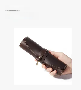 Detailed view of brown vintage leather pencil roll with tie strap and bronze key charm