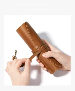 Detail of vintage leather pencil roll showing secure cord closure and bronze key charm