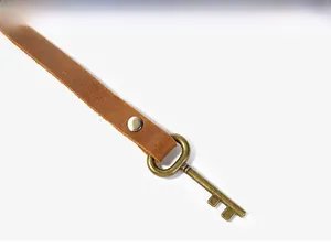 Detail of vintage leather wrap closure with bronze metal stud on a brown pen case