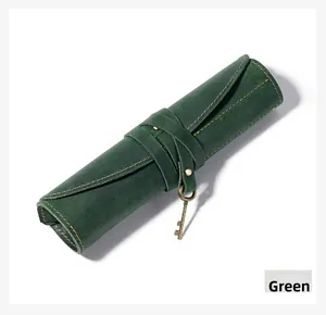 Detail of green crazy horse leather roll-up pencil case with yellow stitching and key charm