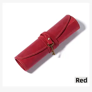 Close-up of vintage red leather pencil roll with antique key charm and stitching