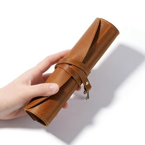 Vintage brown crazy horse leather pencil roll with metal key pendant on white background