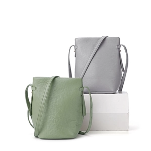 Grüne und graue Eimer-Taschen aus strukturiertem Leder mit verstellbaren Riemen vor weißem Grund