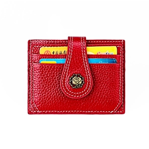 Detail of red litchi leather wallet with bronze rose emblem and white stitching