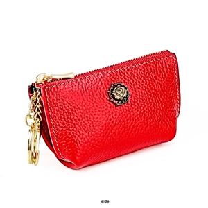 Detail of red pebbled leather coin purse with rose emblem and golden keychain