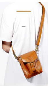 Detail of crazy horse leather messenger bag showing vintage texture on a white t-shirt