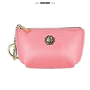 Detailed close-up of pink pebbled leather coin purse with golden rose emblem and keychain