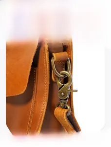 Detailed macro view of vintage bronze lobster clasp on a brown crazy horse leather bag