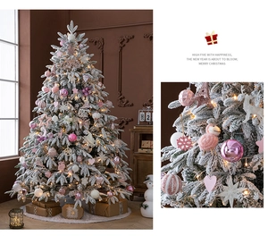 Detail von rosa-weißen Ornamenten und Schneetextur auf einem beleuchteten Weihnachtsbaum