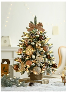 Close-up of snow-flocked Christmas tree with gold ornaments, pine cones, and LED lights