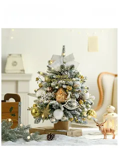 Close-up of mini snowy Christmas tree with gold ornaments and rustic wood base