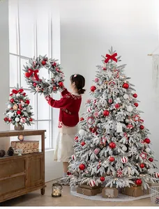 Detailed view of flocked white Christmas tree with red ornaments and matching wreath