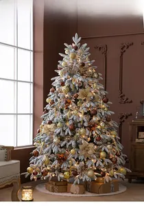 Detail of a flocked Christmas tree featuring warm LED lights and assorted golden ornaments