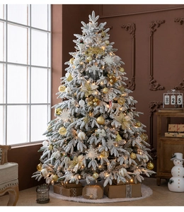 Close-up of a premium flocked snowy Christmas tree with warm LED lights and gold ornaments