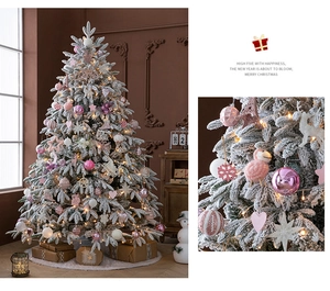 Detail of pink and white holiday ornaments on a flocked artificial snow Christmas tree