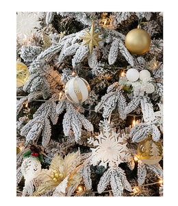 Close-up of snowy PE flocked Christmas tree with gold ornaments and warm LED lights