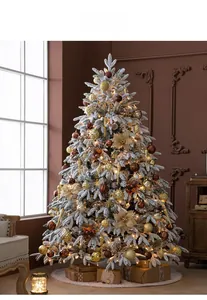 Detail of flocked Christmas tree with warm lights, gold ornaments, and faux snow texture