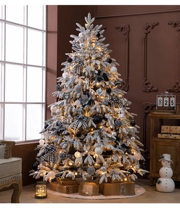 Close-up of a flocked white Christmas tree with warm LED lights and plaid bow ornaments