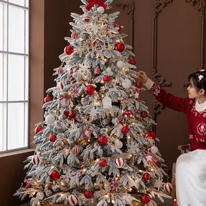 Frosted artificial Christmas tree with red ornaments and warm LED lights for holiday decor