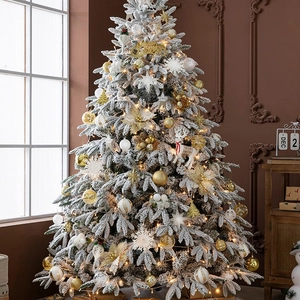 Lush snow-flocked Christmas tree with warm LED lights and elegant gold and white ornaments