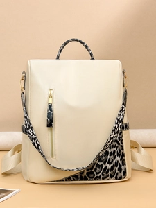 Détail des motifs léopard et des ferrures dorées sur un sac à dos blanc cassé femme