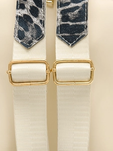 Détail des boucles dorées et motif léopard sur les bretelles de sac en nylon blanc