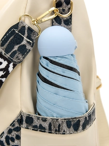 Gros plan d'un mini parapluie bleu clair dans la poche latérale d'un sac à dos beige