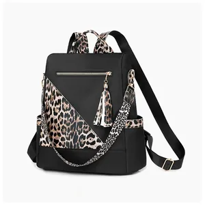 Detail view of leopard print nylon backpack with decorative fringe tassel and side pockets