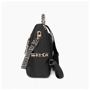 Side view of black nylon backpack featuring leopard print leather trim and gold zippers