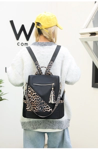 Detail view of water-resistant leopard print backpack with decorative tassel and side pocket