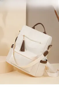 Close-up of cream nylon backpack featuring brown trim details and gold metal zippers