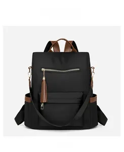 Detail of black nylon backpack with brown leather trim and decorative tassel accents