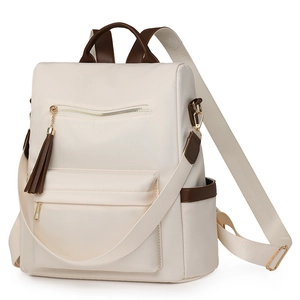 Detail view of the cream nylon backpack featuring brown leather trim and tassel accents