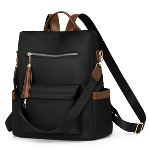 Detail view of black nylon backpack with brown leather accents and stylish fringe tassel