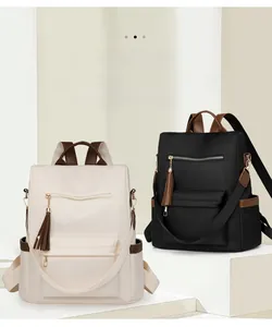 Detail of waterproof nylon backpack showing leather trim, tassel charm and zipper pockets