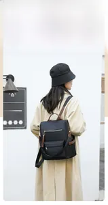 Close-up of black anti-theft nylon backpack for women with brown trim and tassel details
