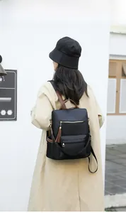 Detail of black nylon backpack with brown leather handle and fringe tassel on female model