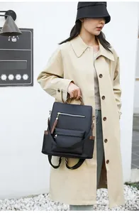 Detail of black nylon backpack with brown leather trim and golden hardware accents