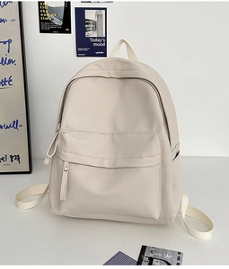 Detail view of a cream-colored high-density nylon backpack with front pocket and side storage