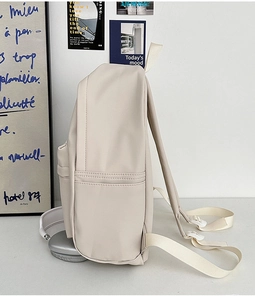 Side view of beige minimalist backpack featuring side storage pocket and waterproof fabric