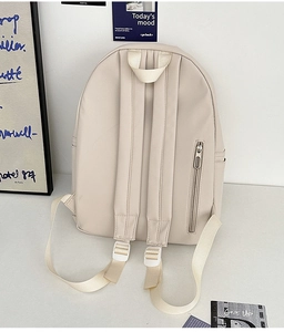 Detail view of cream backpack featuring padded straps and hidden anti-theft back pocket