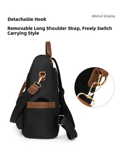 Detailed side view of black nylon backpack featuring brown leather accents and gold hooks