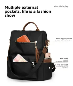 Close-up of black nylon travel backpack with brown leather trim and metal tassel zippers