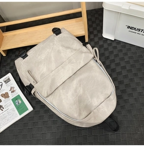 Detailed view of beige nylon streetwear backpack with buckle straps on industrial background