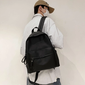 Minimalist black backpack showing high-density nylon fabric and front zipper pocket detail