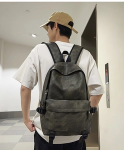 Deep grey faux leather backpack shown on male model featuring wide comfortable straps
