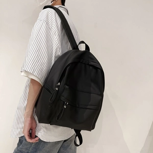 Detail of minimalist black nylon backpack featuring dual zipper pockets and wide straps